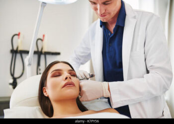 Young female doctor performing a botox injection to the forehead of a mature woman lying on a table in a beauty clinic