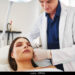 Young female doctor performing a botox injection to the forehead of a mature woman lying on a table in a beauty clinic